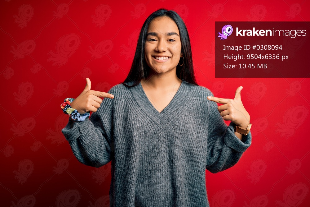Young beautiful asian woman wearing casual sweater standing over isolated red background looking confident with smile on face, pointing oneself with fingers proud and happy.