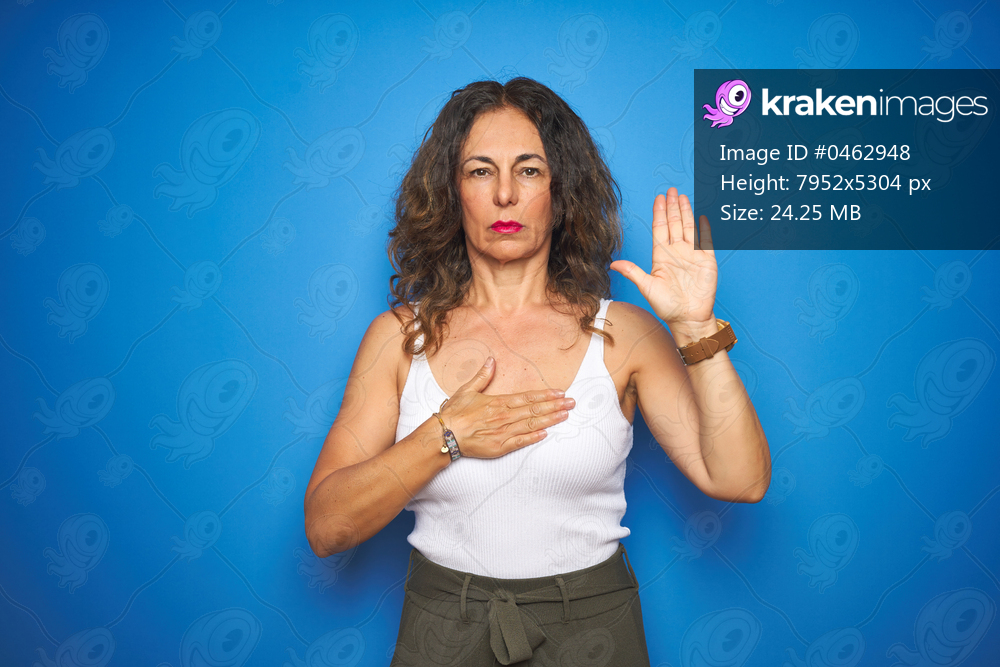 Middle age senior woman with curly hair standing over blue isolated background Swearing with hand on chest and open palm, making a loyalty promise oath