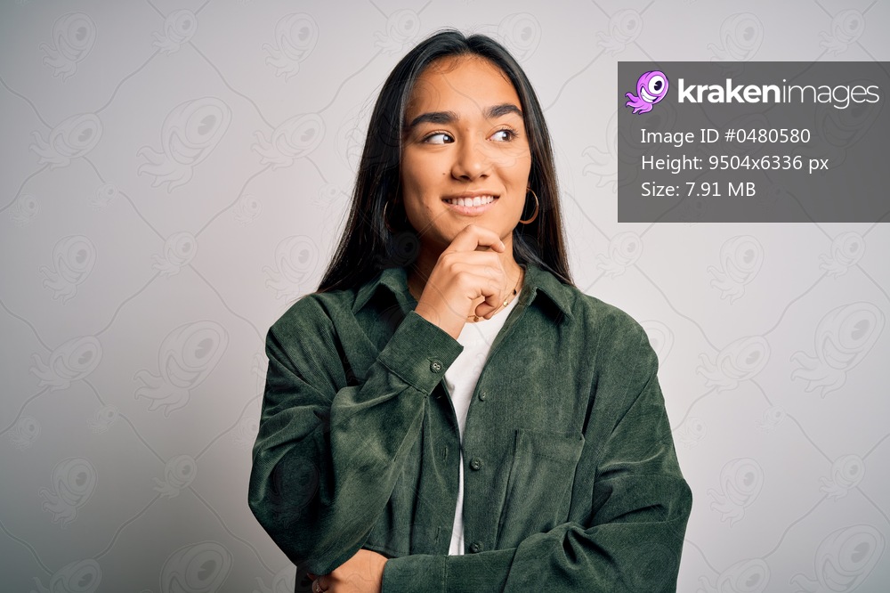 Young beautiful asian woman wearing casual shirt standing over isolated white background with hand on chin thinking about question, pensive expression. Smiling with thoughtful face. Doubt concept.