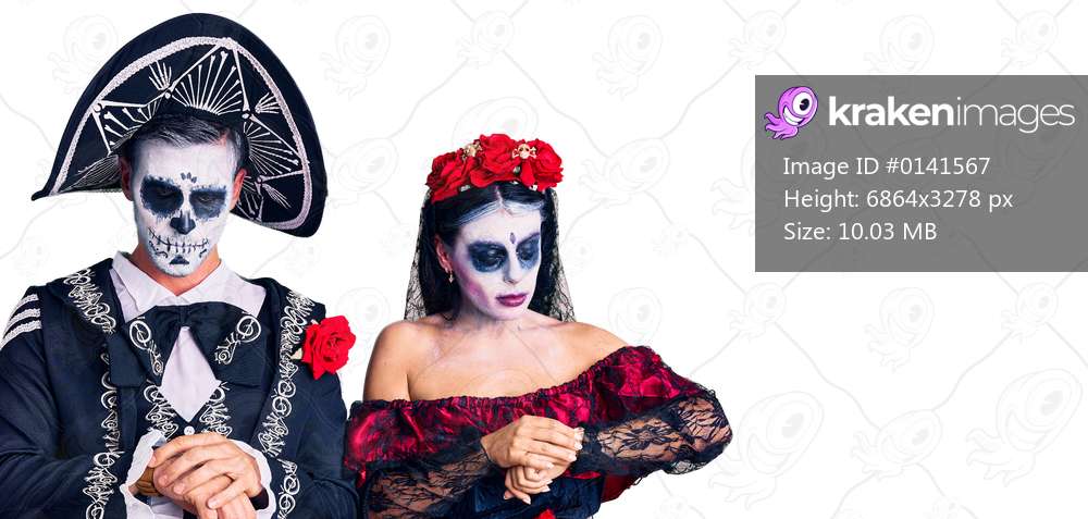 Young couple wearing mexican day of the dead costume over background checking the time on wrist watch, relaxed and confident 