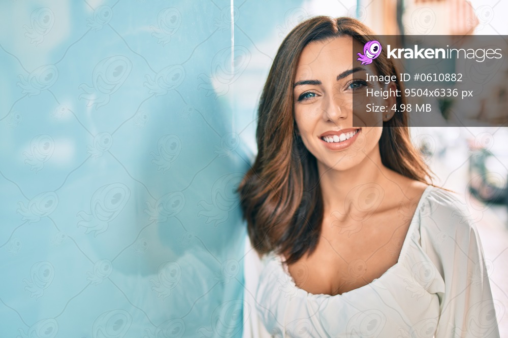 Young hispanic woman smiling happy leaning on the wall at the city.