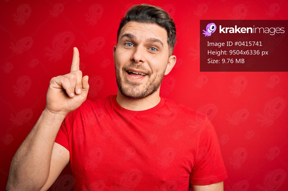 Young man with blue eyes wearing casual t-shirt over red isolated background pointing finger up with successful idea. Exited and happy. Number one.