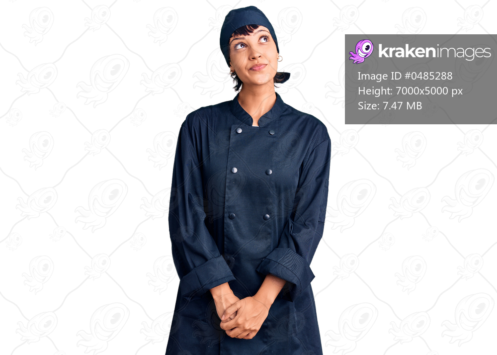 Young brunette woman with short hair wearing professional cook uniform smiling looking to the side and staring away thinking. 