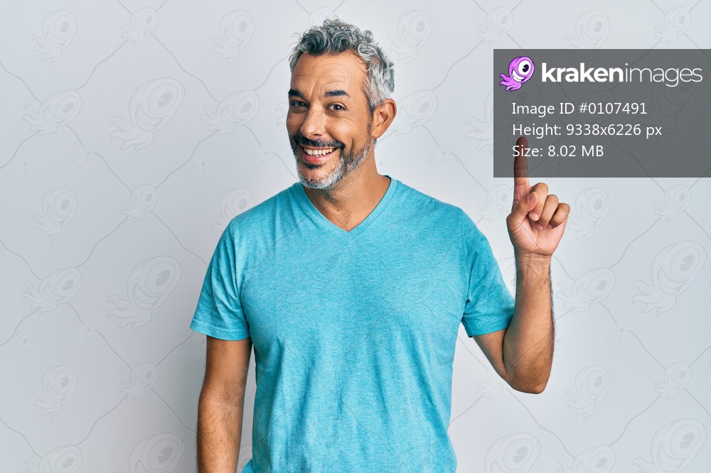 Middle age grey-haired man wearing casual clothes showing and pointing up with finger number one while smiling confident and happy. 