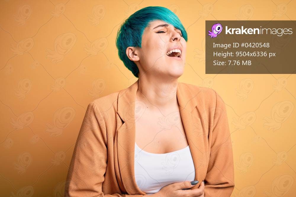 Young beautiful woman with blue fashion hair wearing casual jacket over yellow background with hand on stomach because nausea, painful disease feeling unwell. Ache concept.