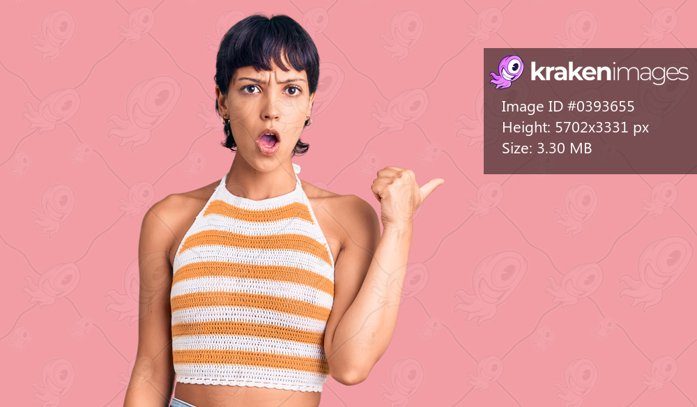 Young brunette woman with short hair wearing casual clothes surprised pointing with hand finger to the side, open mouth amazed expression. 