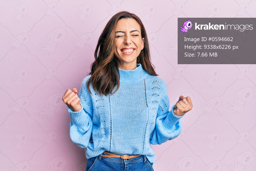 Young brunette woman wearing casual winter sweater over pink background excited for success with arms raised and eyes closed celebrating victory smiling. winner concept. 