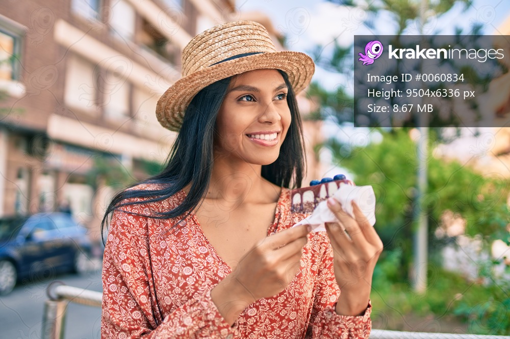 Young african american tourist woman on vacation eating cake at the city.
