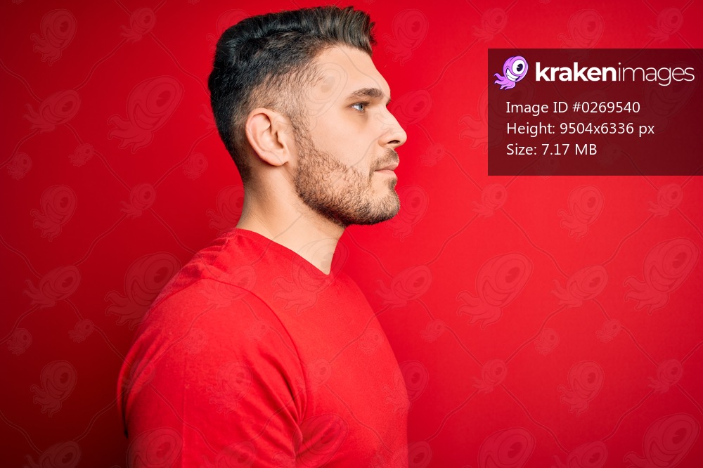 Young man with blue eyes wearing casual t-shirt over red isolated background looking to side, relax profile pose with natural face with confident smile.
