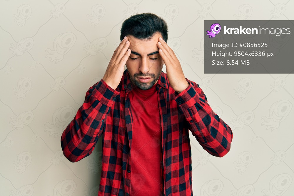 Young hispanic man wearing casual clothes with hand on head, headache because stress. suffering migraine. 