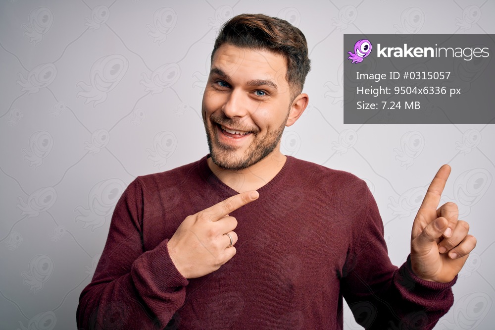 Young man with blue eyes wearing casual sweater standing over isolated background smiling and looking at the camera pointing with two hands and fingers to the side.