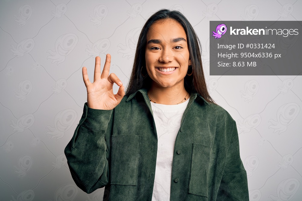 Young beautiful asian woman wearing casual shirt standing over isolated white background smiling positive doing ok sign with hand and fingers. Successful expression.