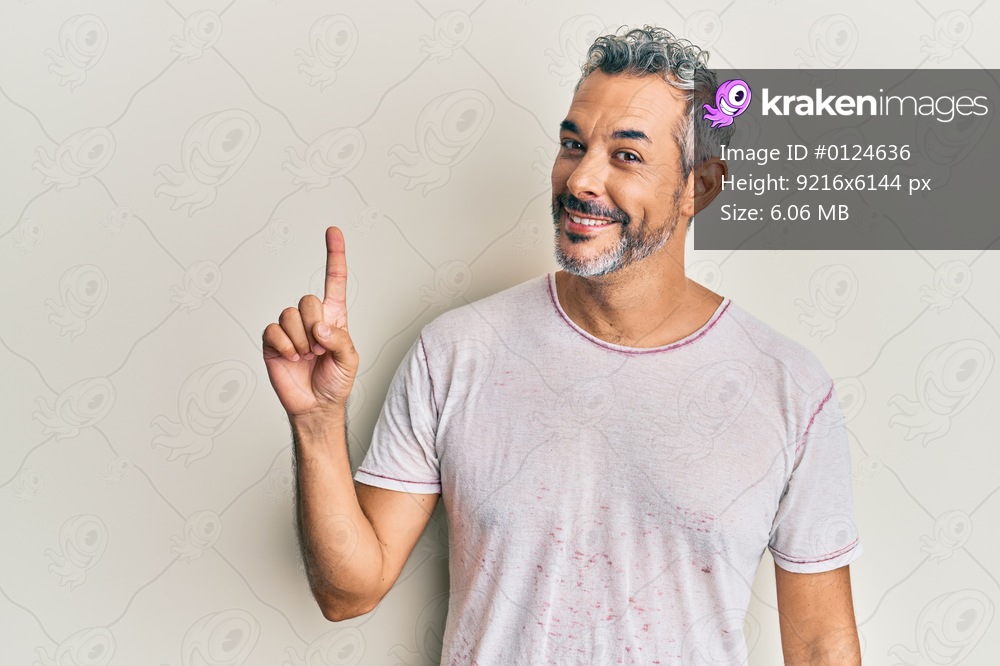 Middle age grey-haired man wearing casual clothes showing and pointing up with finger number one while smiling confident and happy. 