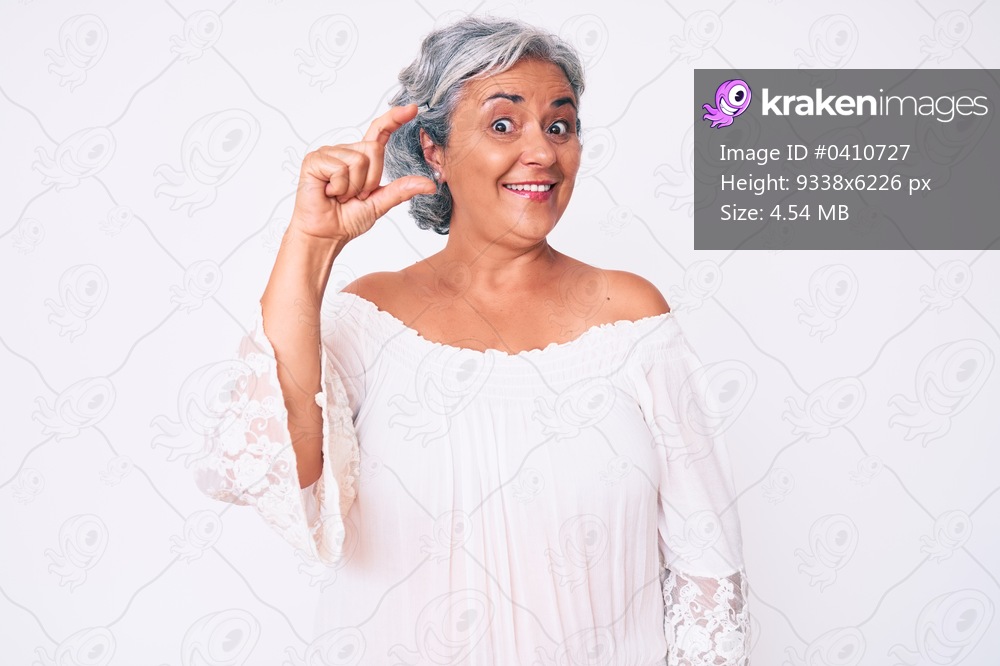 Senior hispanic grey- haired woman wearing casual clothes smiling and confident gesturing with hand doing small size sign with fingers looking and the camera. measure concept. 
