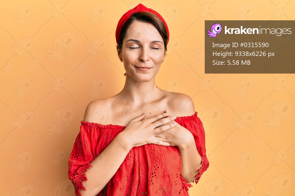 Young brunette woman with short hair wearing casual clothes smiling with hands on chest with closed eyes and grateful gesture on face. health concept. 
