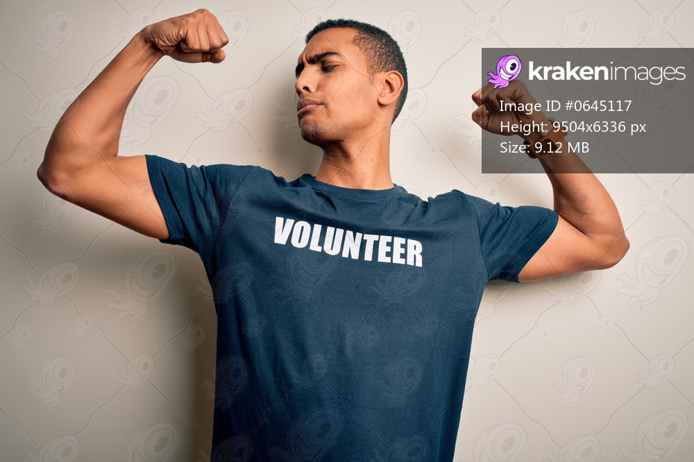 Young handsome african american man volunteering wearing t-shirt with volunteer message showing arms muscles smiling proud. Fitness concept.