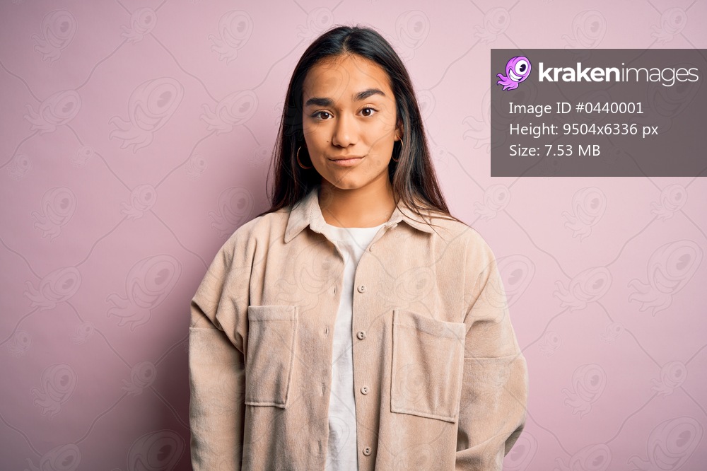 Young beautiful asian woman wearing casual shirt standing over pink background Relaxed with serious expression on face. Simple and natural looking at the camera.