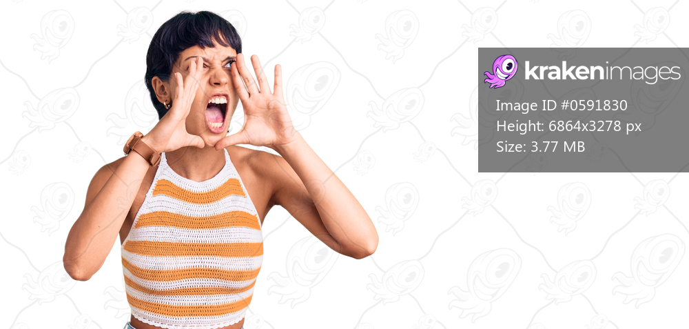 Young brunette woman with short hair wearing casual clothes shouting angry out loud with hands over mouth 