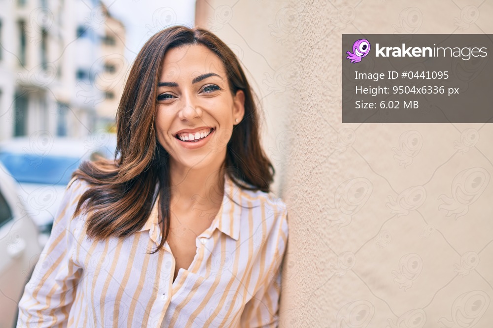 Young hispanic woman smiling happy leaning on the wall at the city.