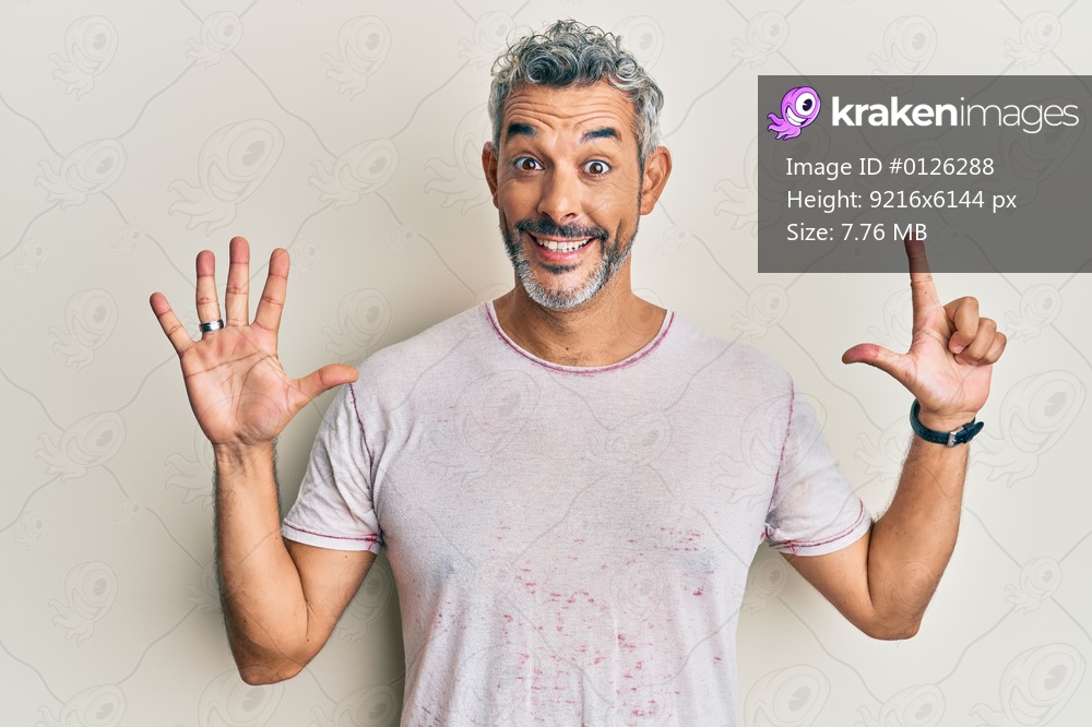 Middle age grey-haired man wearing casual clothes showing and pointing up with fingers number seven while smiling confident and happy. 