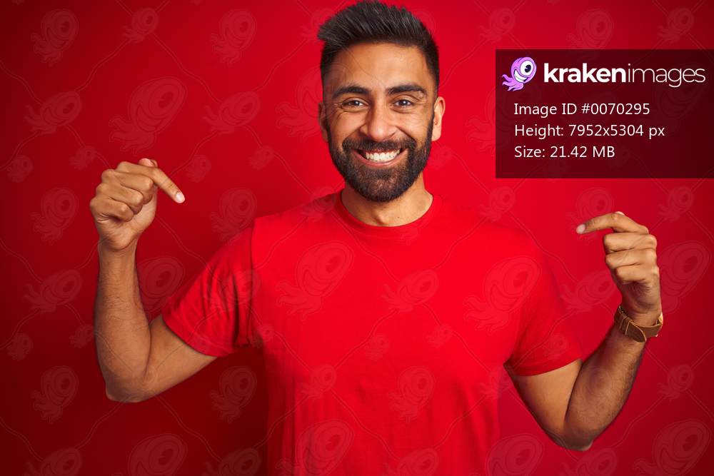 Young handsome indian man wearing t-shirt over isolated red background looking confident with smile on face, pointing oneself with fingers proud and happy.