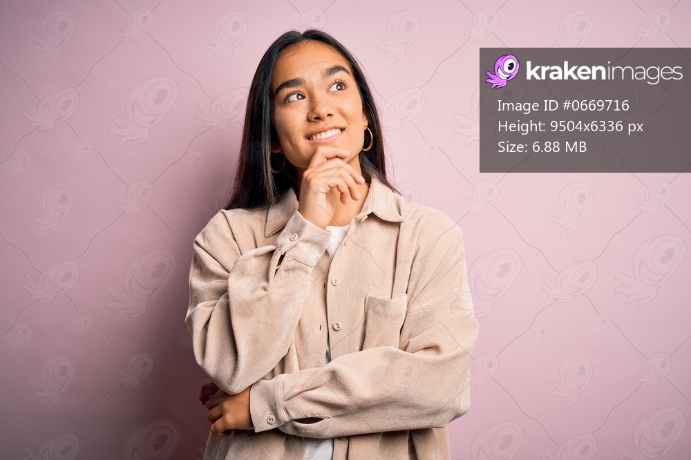 Young beautiful asian woman wearing casual shirt standing over pink background with hand on chin thinking about question, pensive expression. Smiling and thoughtful face. Doubt concept.