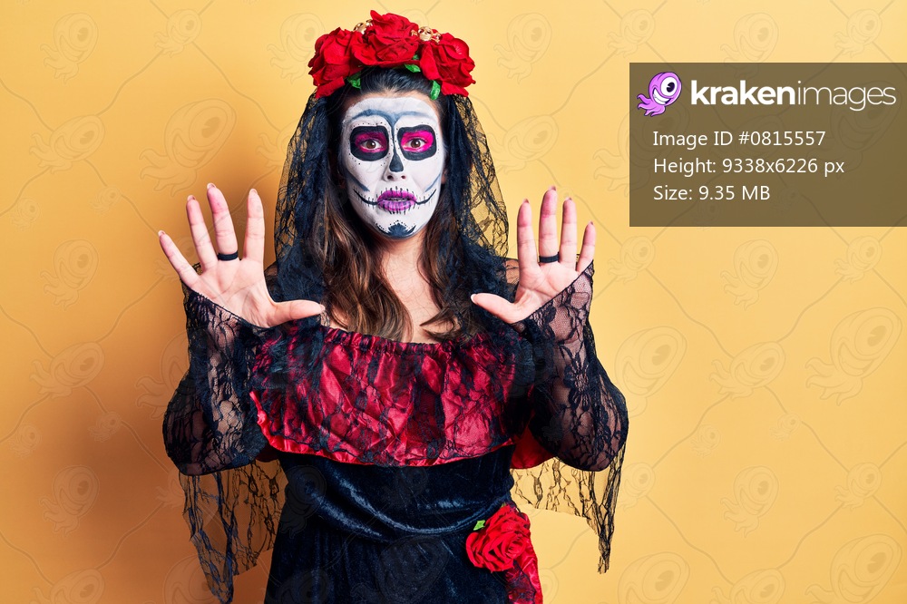Young woman wearing day of the dead costume over yellow afraid and terrified with fear expression stop gesture with hands, shouting in shock. panic concept. 