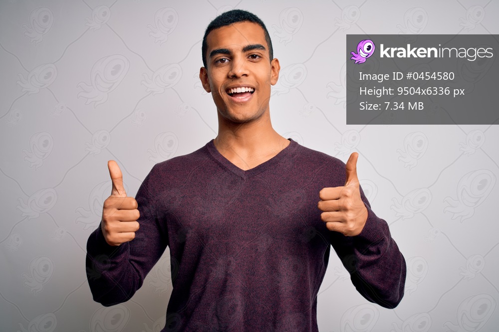 Young handsome african american man wearing casual sweater over white background success sign doing positive gesture with hand, thumbs up smiling and happy. Cheerful expression and winner gesture.