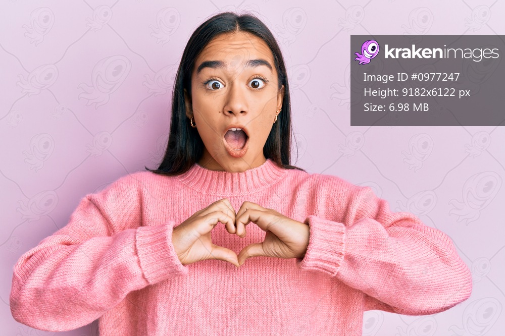Young asian woman doing heart symbol with hands afraid and shocked with surprise and amazed expression, fear and excited face. 