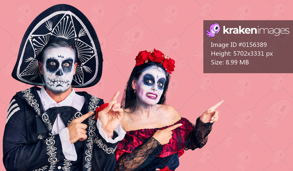 Young couple wearing mexican day of the dead costume over background pointing aside worried and nervous with both hands, concerned and surprised expression 
