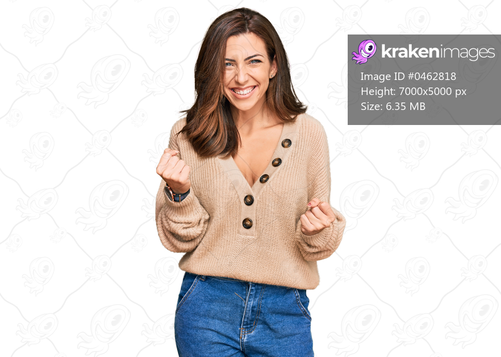 Young brunette woman wearing casual winter sweater very happy and excited doing winner gesture with arms raised, smiling and screaming for success. celebration concept. 