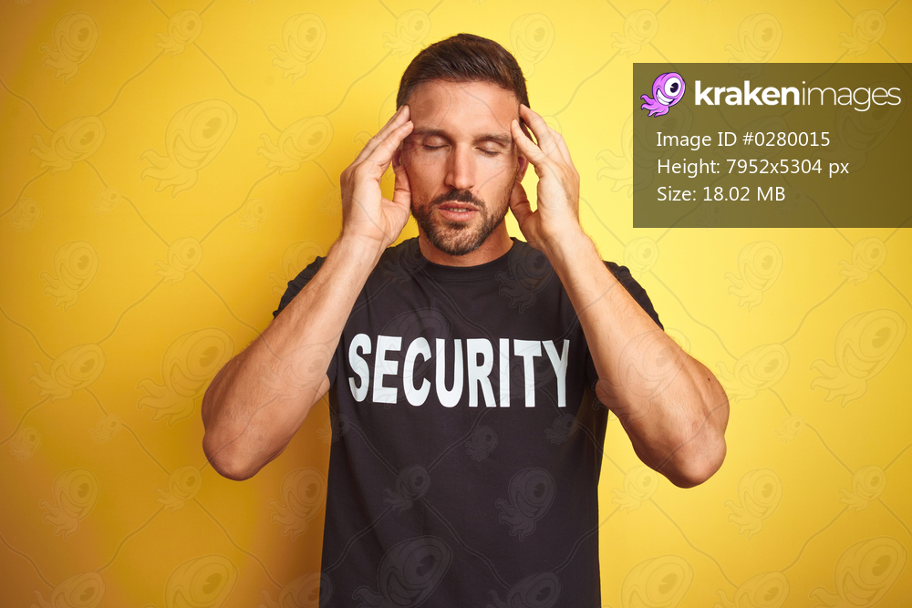 Young safeguard man wearing security uniform over yellow isolated background with hand on head for pain in head because stress. Suffering migraine.
