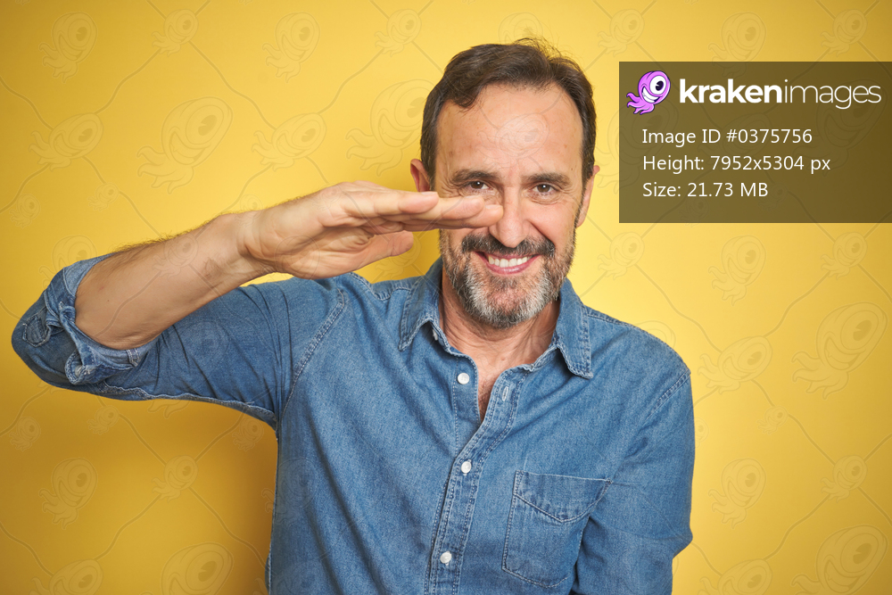 Handsome middle age senior man with grey hair over isolated yellow background gesturing with hands showing big and large size sign, measure symbol. Smiling looking at the camera. Measuring concept.