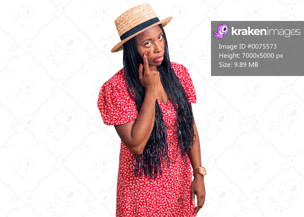 Young african american woman wearing summer hat pointing to the eye watching you gesture, suspicious expression 