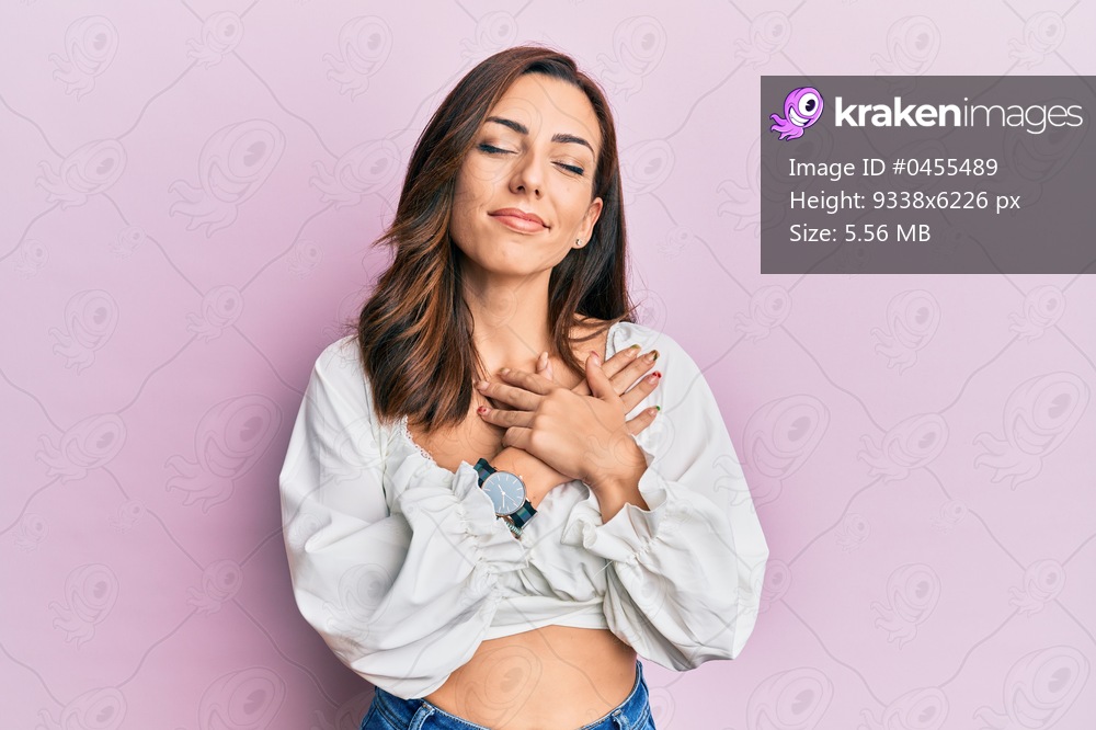 Young brunette woman wearing casual clothes over pink smiling with hands on chest, eyes closed with grateful gesture on face. health concept. 