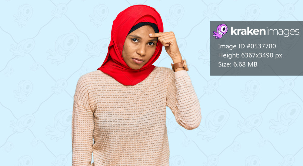Young african american woman wearing traditional islamic hijab scarf pointing unhappy to pimple on forehead, ugly infection of blackhead. acne and skin problem 