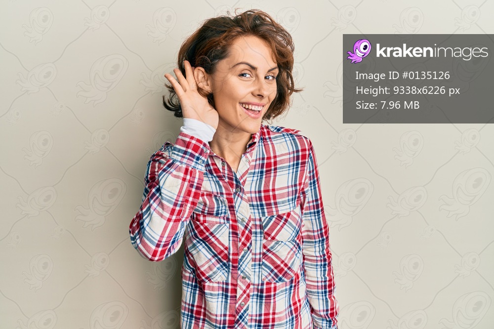 Young brunette woman wearing casual clothes smiling with hand over ear listening and hearing to rumor or gossip. deafness concept. 