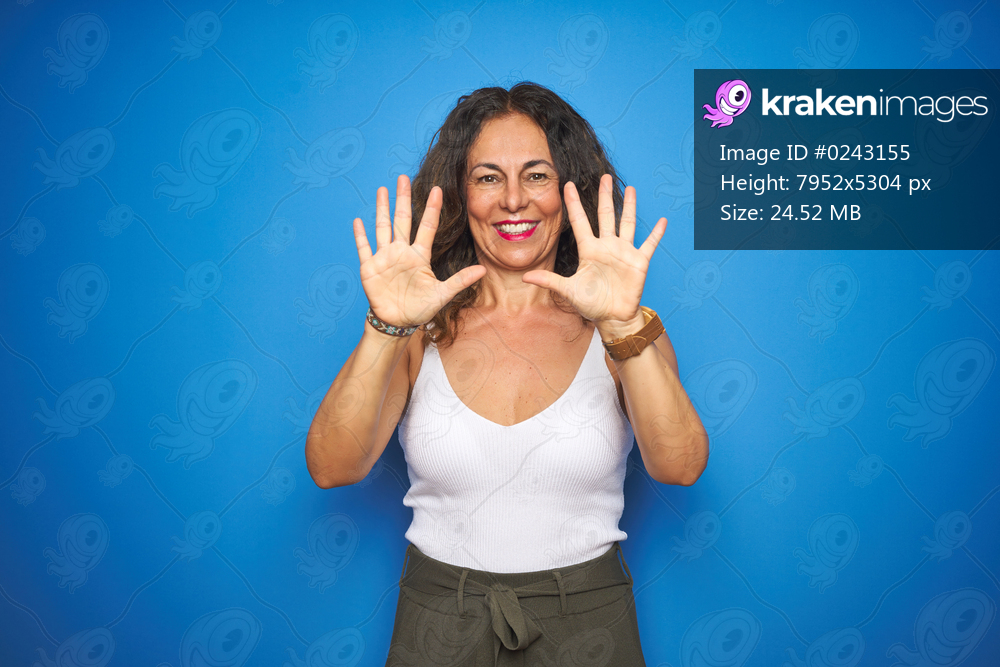 Middle age senior woman with curly hair standing over blue isolated background showing and pointing up with fingers number ten while smiling confident and happy.