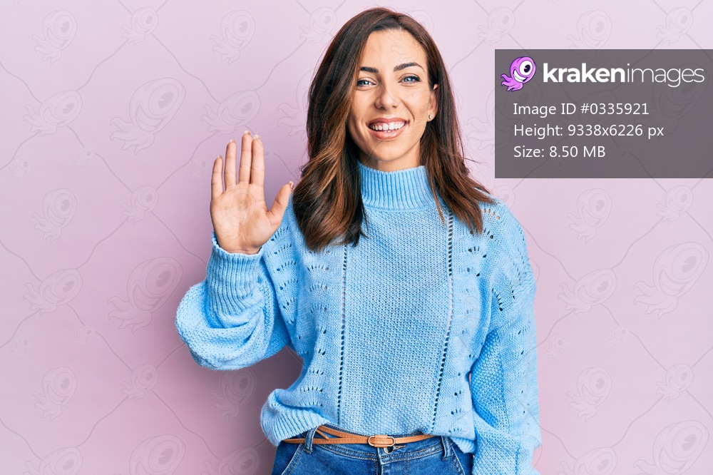 Young brunette woman wearing casual winter sweater over pink background showing and pointing up with fingers number five while smiling confident and happy. 