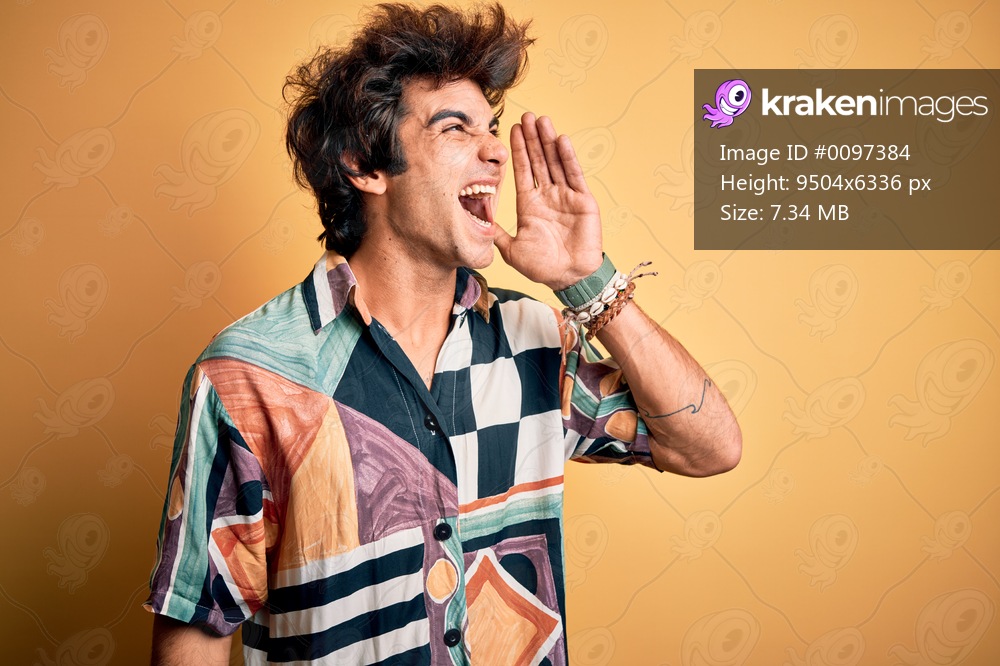 Young handsome man on vacation wearing summer shirt over isolated yellow background shouting and screaming loud to side with hand on mouth. Communication concept.