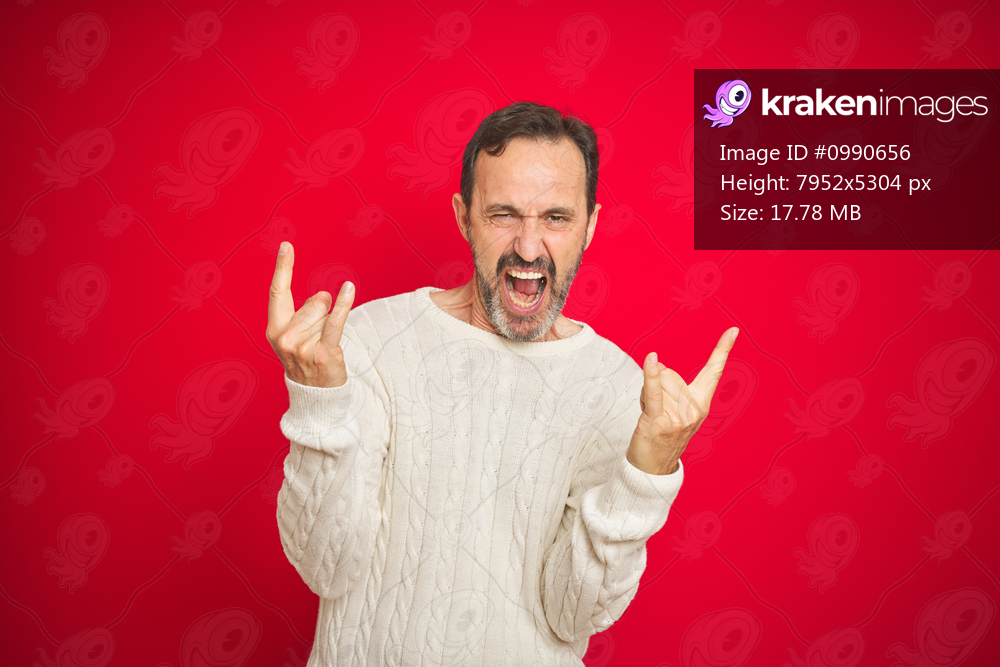 Handsome middle age senior man with grey hair over isolated red background shouting with crazy expression doing rock symbol with hands up. Music star. Heavy music concept.