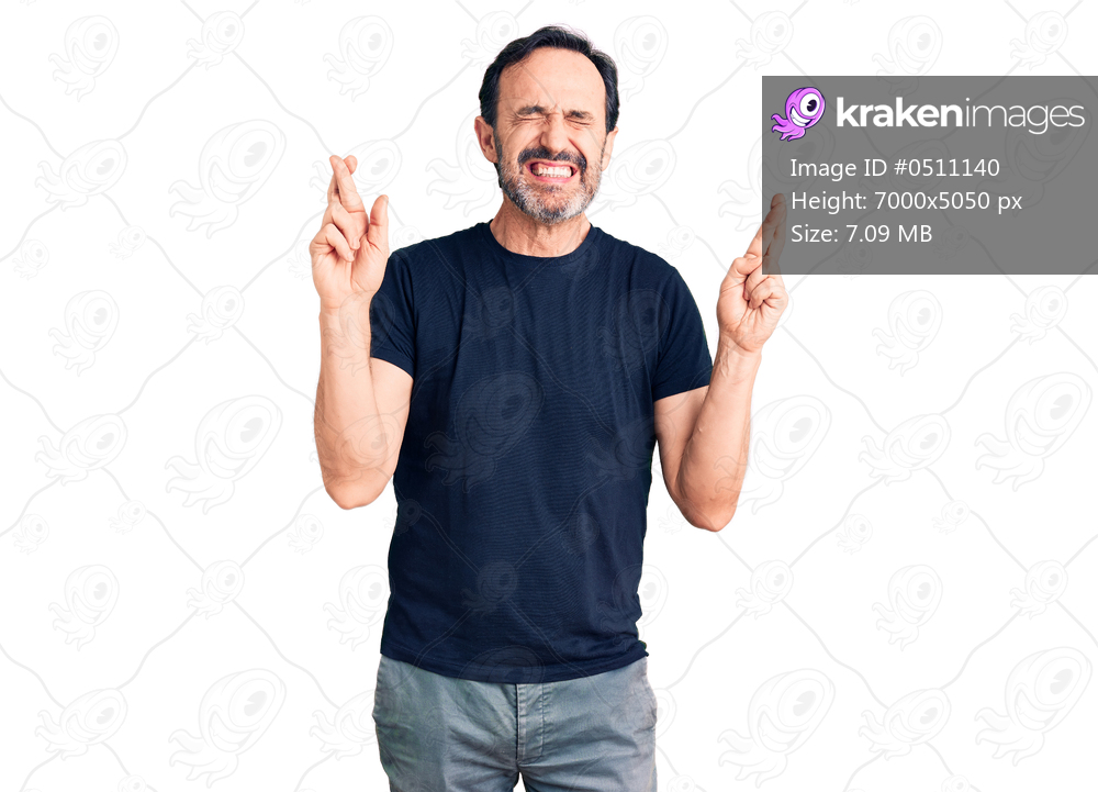 Middle age handsome man wearing casual t-shirt gesturing finger crossed smiling with hope and eyes closed. luck and superstitious concept. 