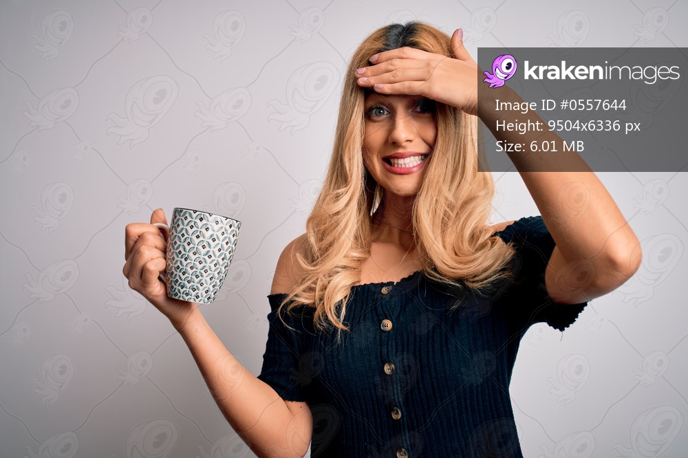 Young beautiful blonde woman drinking mug of coffee over isolated white background stressed with hand on head, shocked with shame and surprise face, angry and frustrated. Fear and upset for mistake.