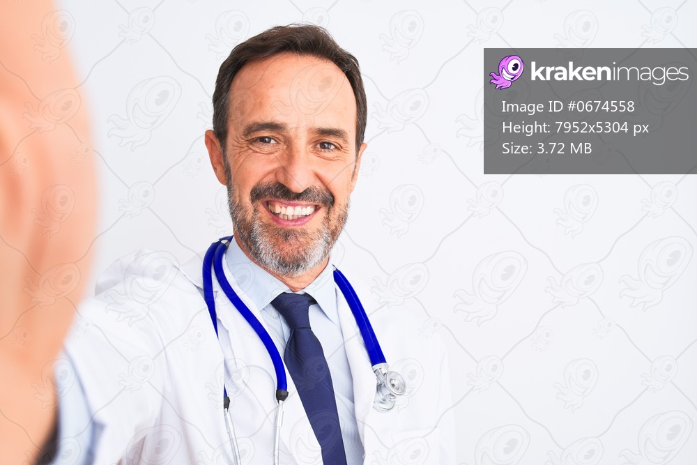 Middle age doctor man wearing stethoscope make selfie over isolated white background with a happy face standing and smiling with a confident smile showing teeth