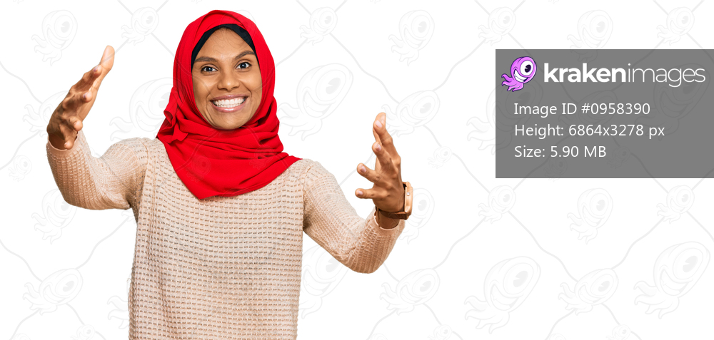 Young african american woman wearing traditional islamic hijab scarf looking at the camera smiling with open arms for hug. cheerful expression embracing happiness. 