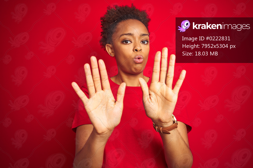 Young beautiful african american woman with afro hair over isolated red background Moving away hands palms showing refusal and denial with afraid and disgusting expression. Stop and forbidden.