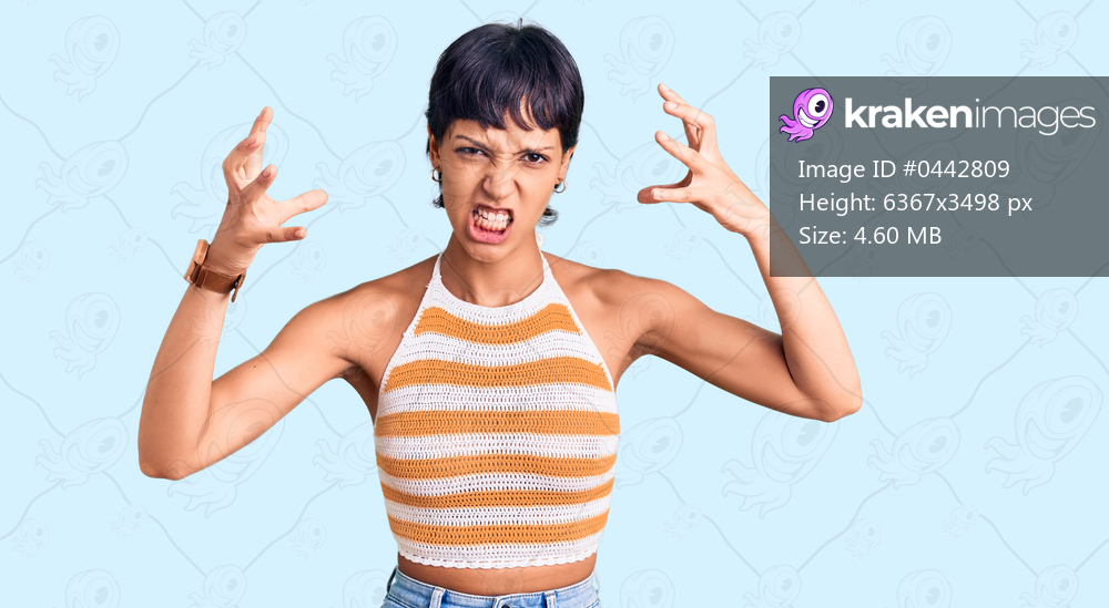 Young brunette woman with short hair wearing casual clothes shouting frustrated with rage, hands trying to strangle, yelling mad 