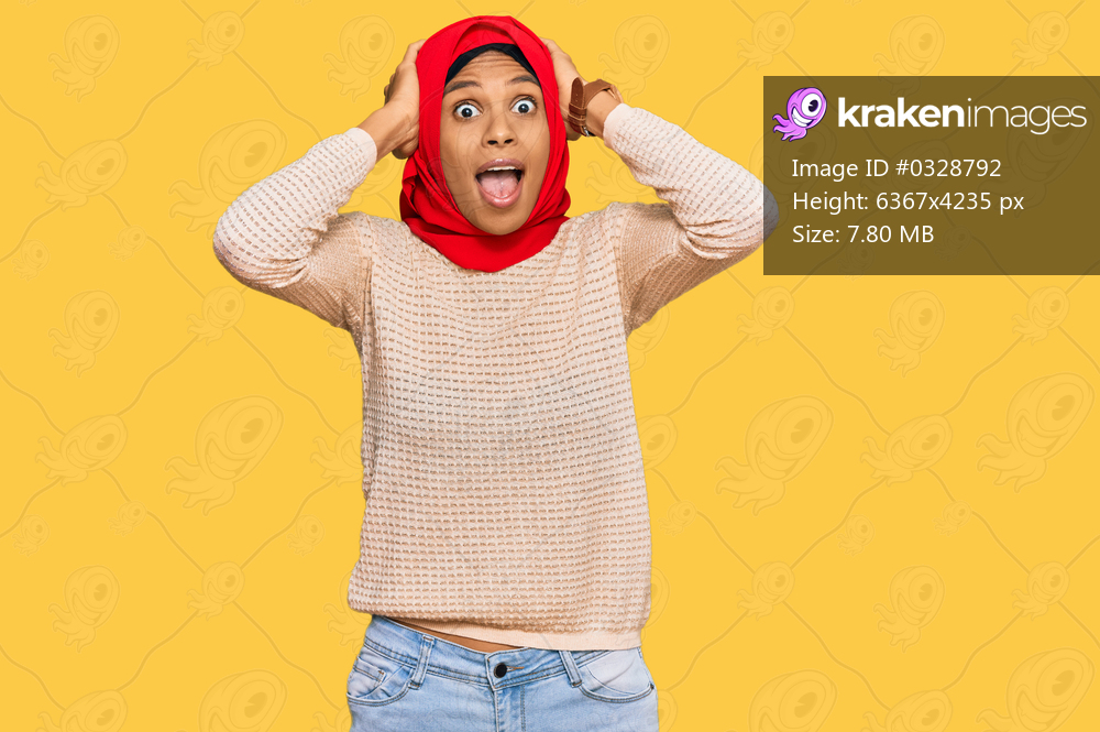 Young african american woman wearing traditional islamic hijab scarf crazy and scared with hands on head, afraid and surprised of shock with open mouth 