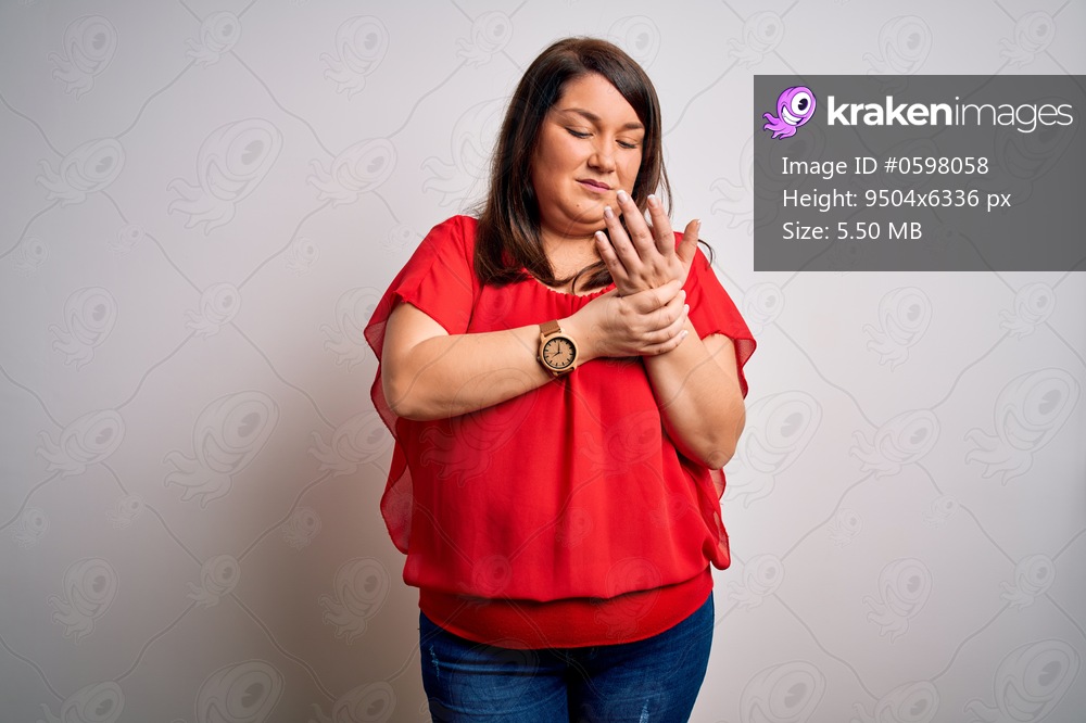 Beautiful brunette plus size woman wearing casual red t-shirt over isolated white background Suffering pain on hands and fingers, arthritis inflammation