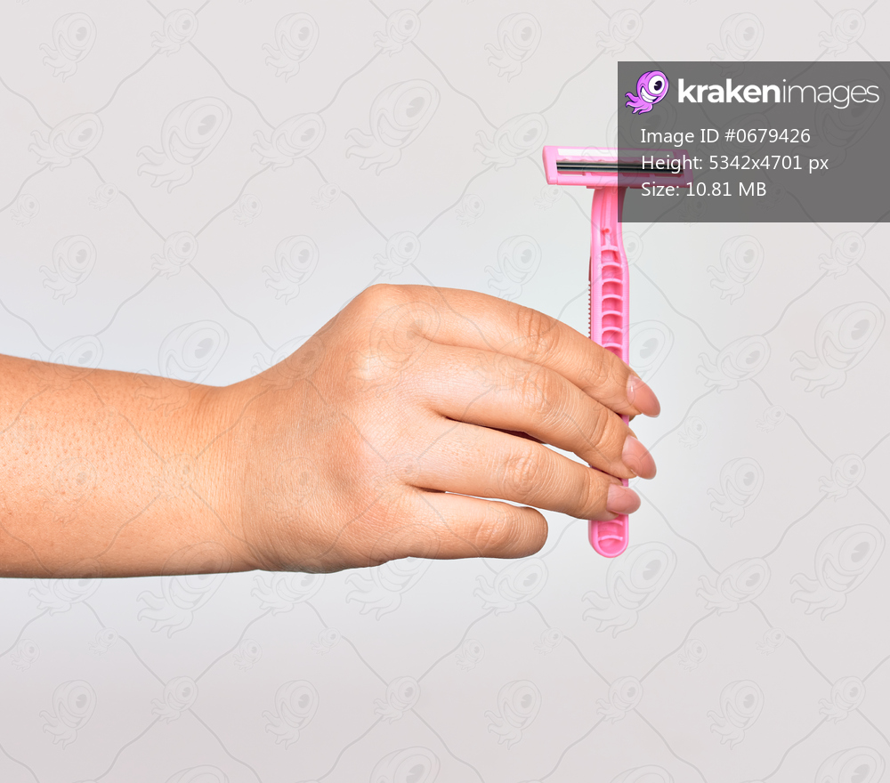 Hand of caucasian young woman holding pink razor over isolated white background